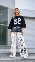 Front view of woman wearing black oversized graphic t-shirt and printed wide-leg pants set