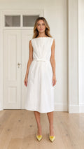 Front full view of woman wearing white sleeveless boatneck pleated midi dress with waist bow