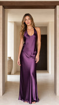 Front view of woman wearing plum purple halter backless satin maxi dress