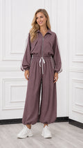 Front view of woman wearing a mauve long sleeve zip-up track jumpsuit with white side stripes