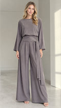 Front full view of woman wearing a slate grey long-sleeve wide-leg jumpsuit with tie waist