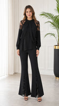 Front full-length view of model wearing black long sleeve lace patchwork top and matching flare pants set