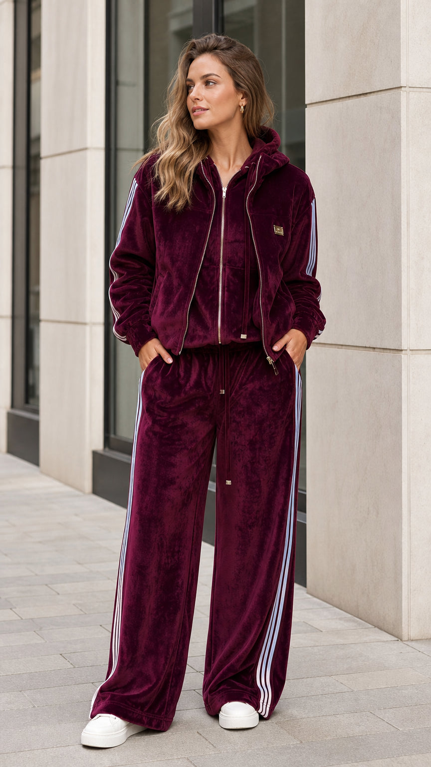 Front view of woman wearing burgundy velour zip-up hoodie and wide-leg tracksuit set with side stripes