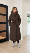 Front full view of women's long belted maxi puffer coat in chocolate brown