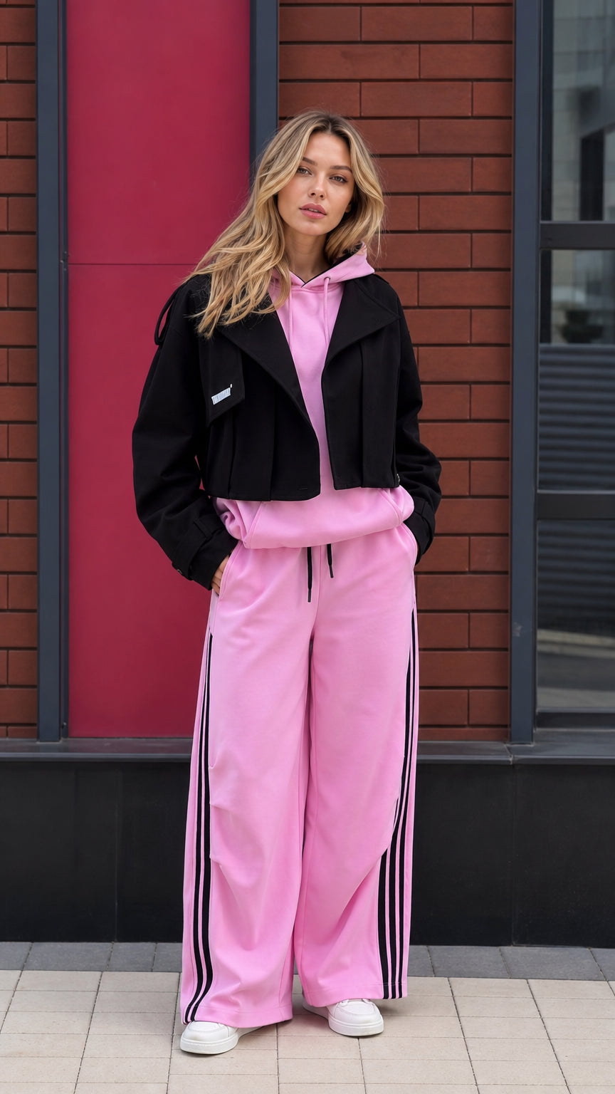 Model wearing pink hoodie, matching wide-leg sweatpants, and black cropped jacket full front view