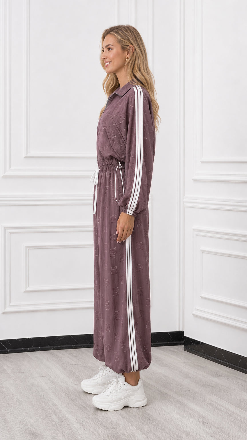 Side profile of woman wearing a mauve sporty jumpsuit with side stripe detail