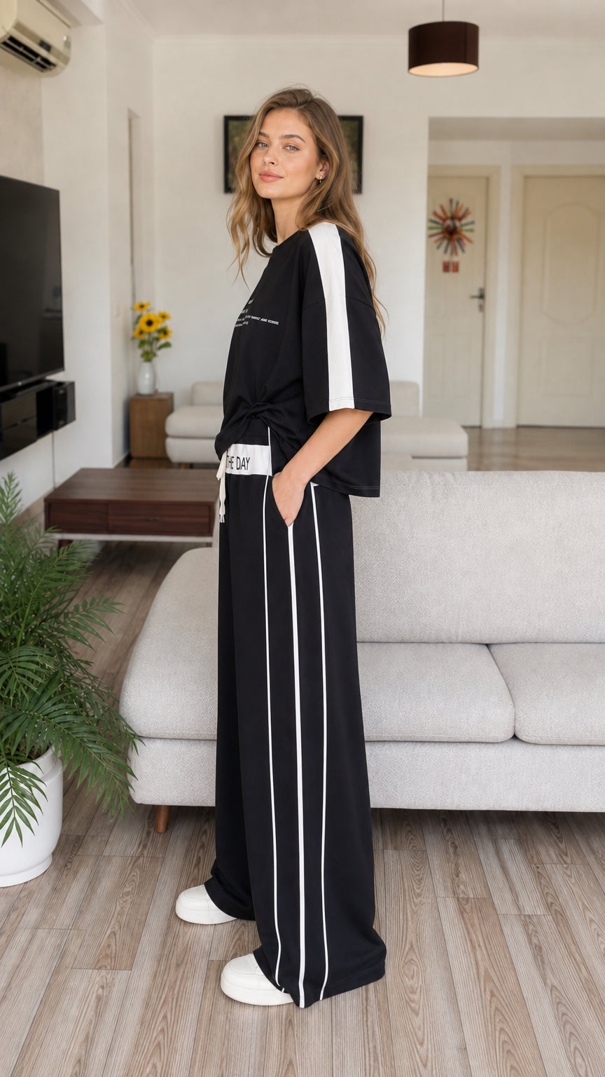 Side 3/4 view of model in black loungewear set with hands in pant pockets