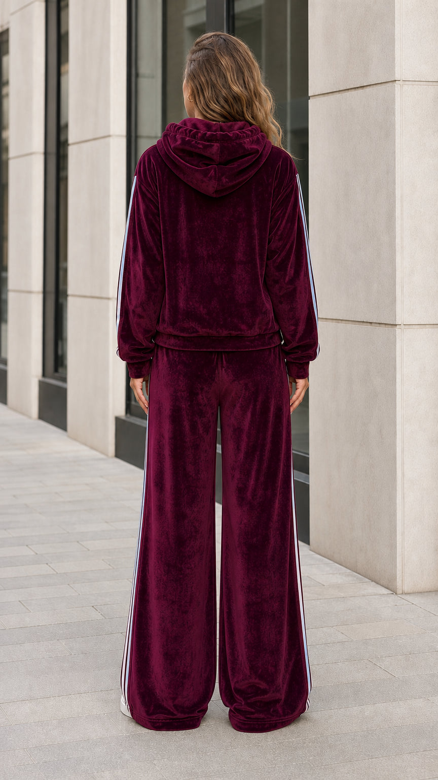 Back view of woman wearing burgundy velour hooded tracksuit with wide-leg pants