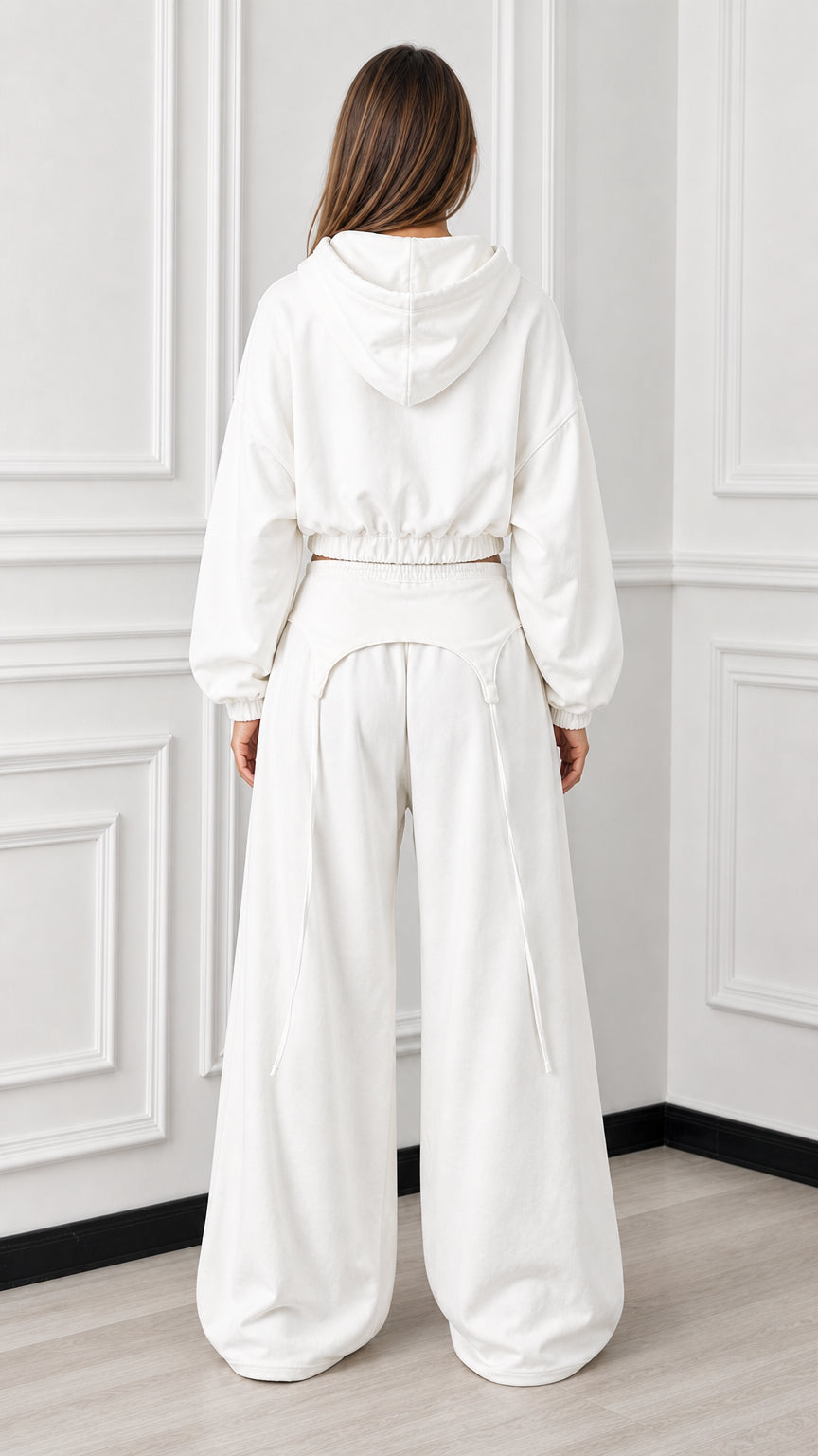 Back view of woman wearing white hooded cropped sweatshirt and wide leg track pants