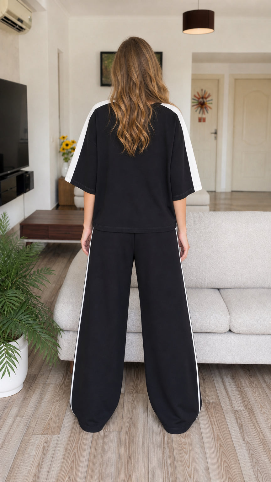 Back view of model wearing oversized black t-shirt and wide-leg pants