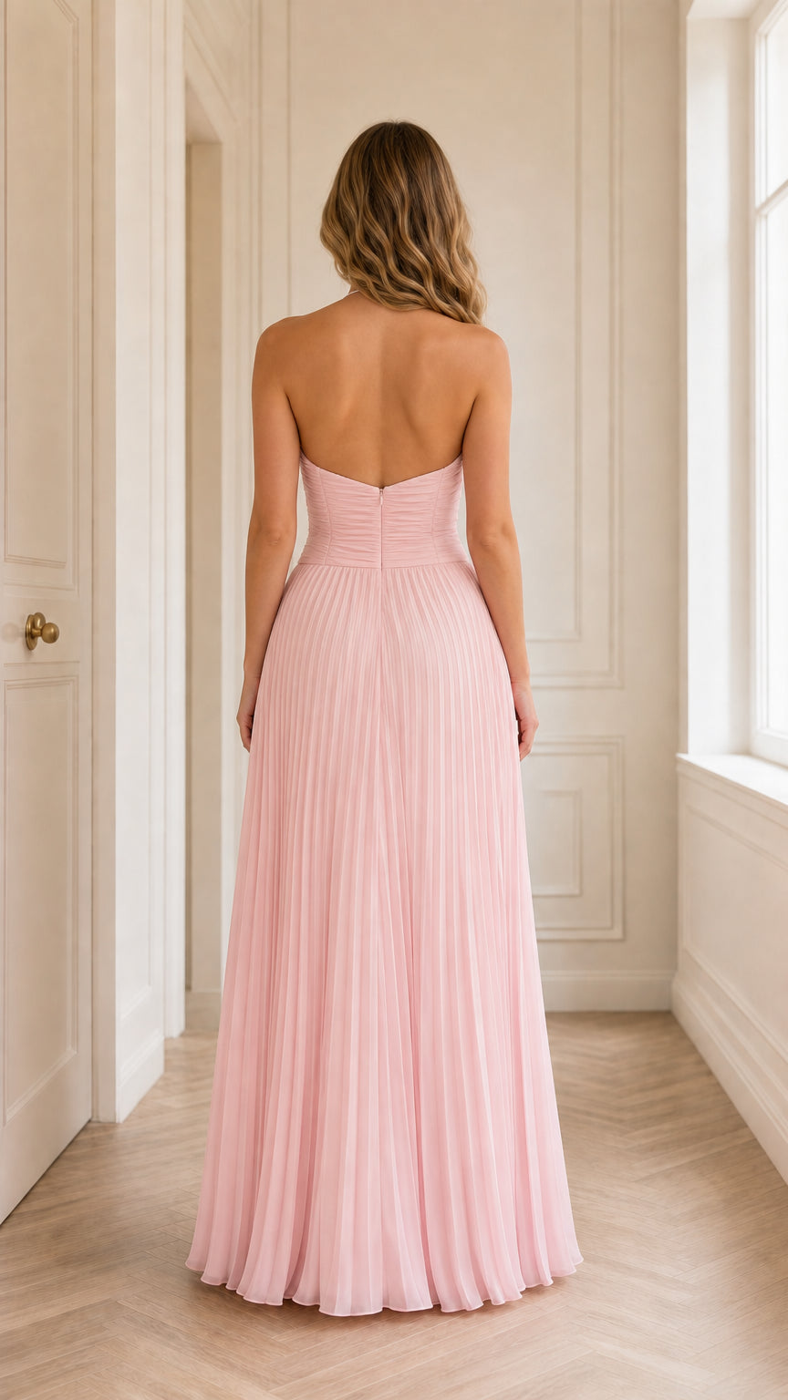 Back view of woman wearing open-back blush pink pleated maxi dress