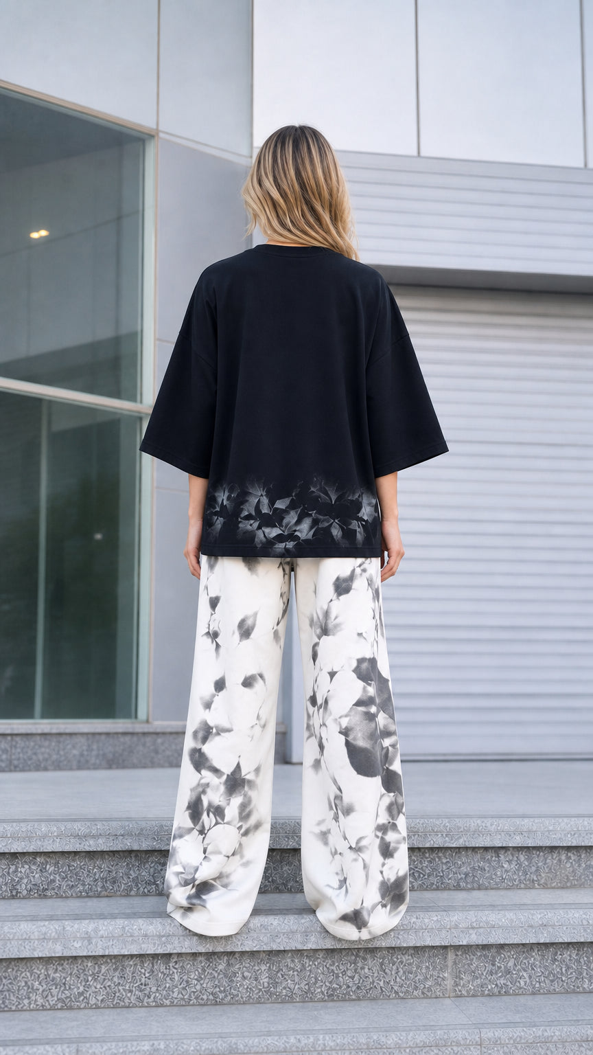 Back view of woman wearing relaxed black drop-shoulder top and wide-leg trousers