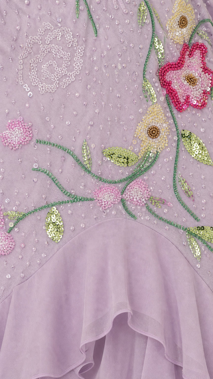 Close-up detail of floral beadwork, sequins, and layered chiffon ruffle hem on lavender dress