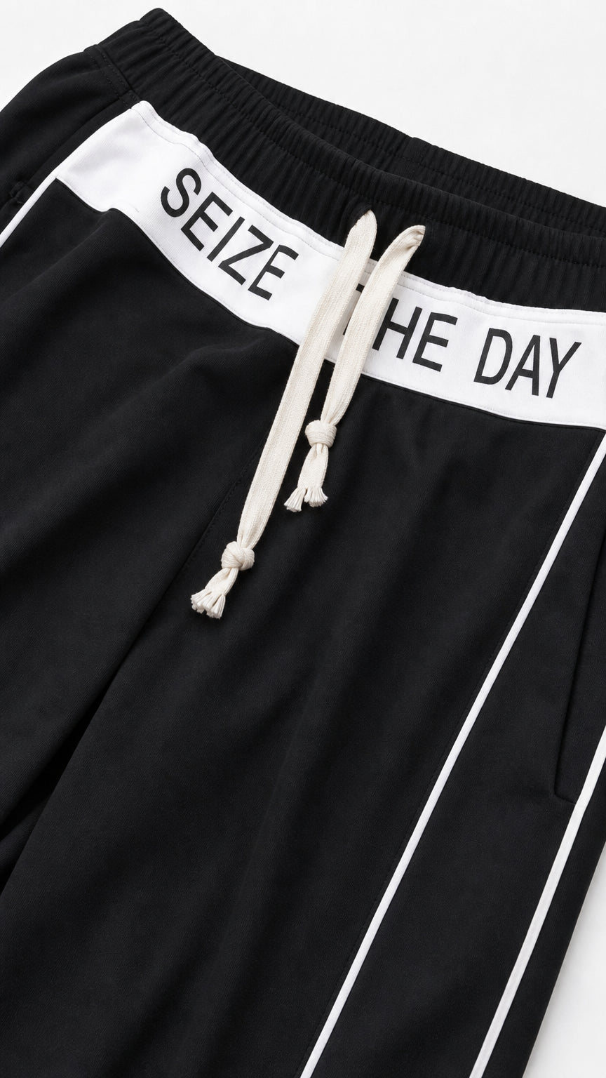Close-up detail of black pant waistband with white Seize The Day lettering and drawstring