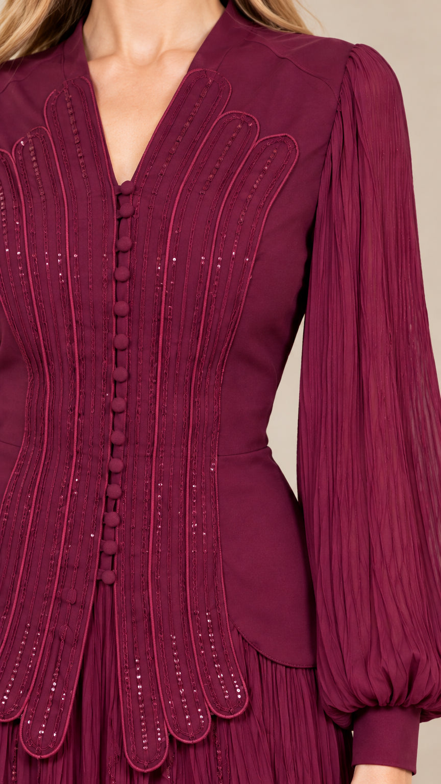Close-up detail of burgundy bodice showing covered buttons and textured pleating