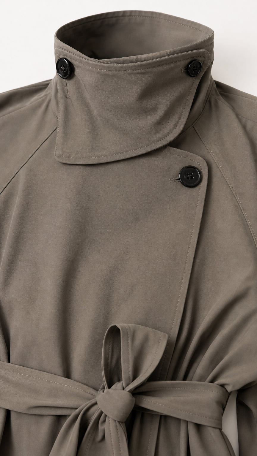 Close-up detail of high stand buttoned collar and waist belt knot on trench coat