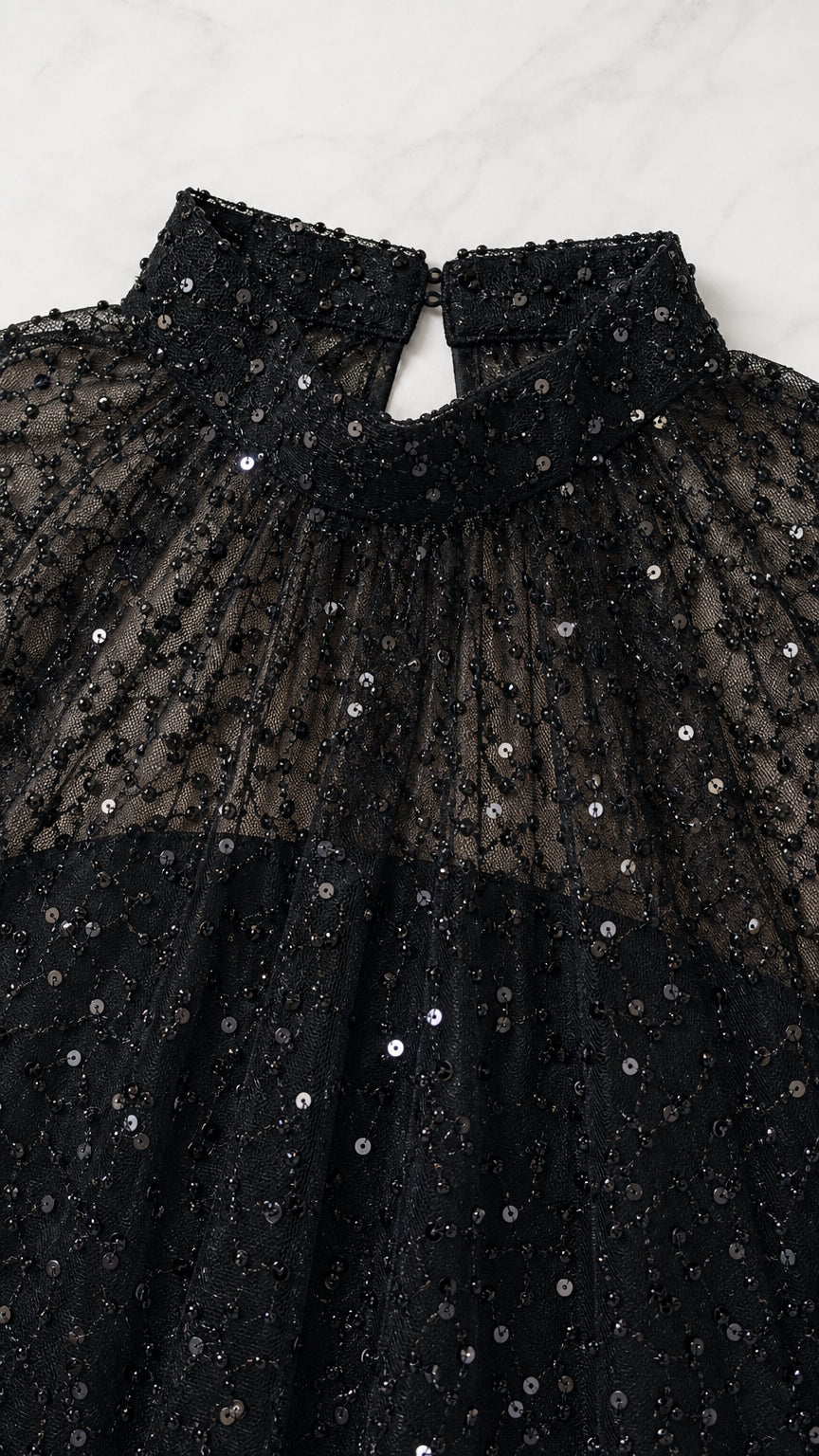 Close-up detail of high neck black sheer mesh capelet with shimmering sequins