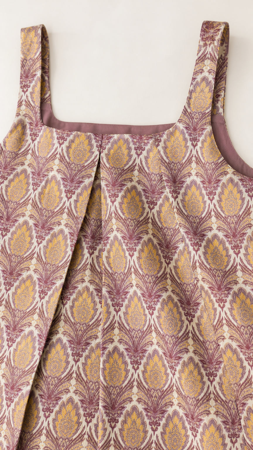 Close-up detail of square neckline and front pleat on damask printed fabric