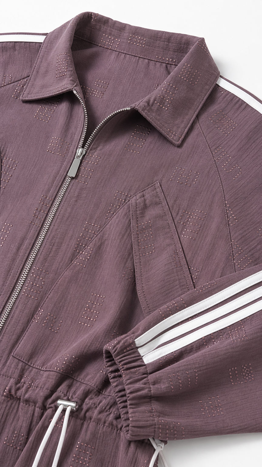 Close-up detail of textured fabric, collar, chest pocket, and zipper on mauve track jumpsuit