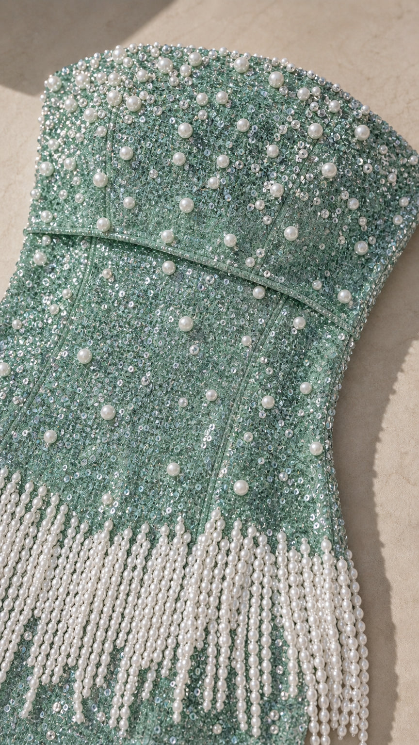 Close-up detail of mint green sequin fabric and faux pearl beaded fringe